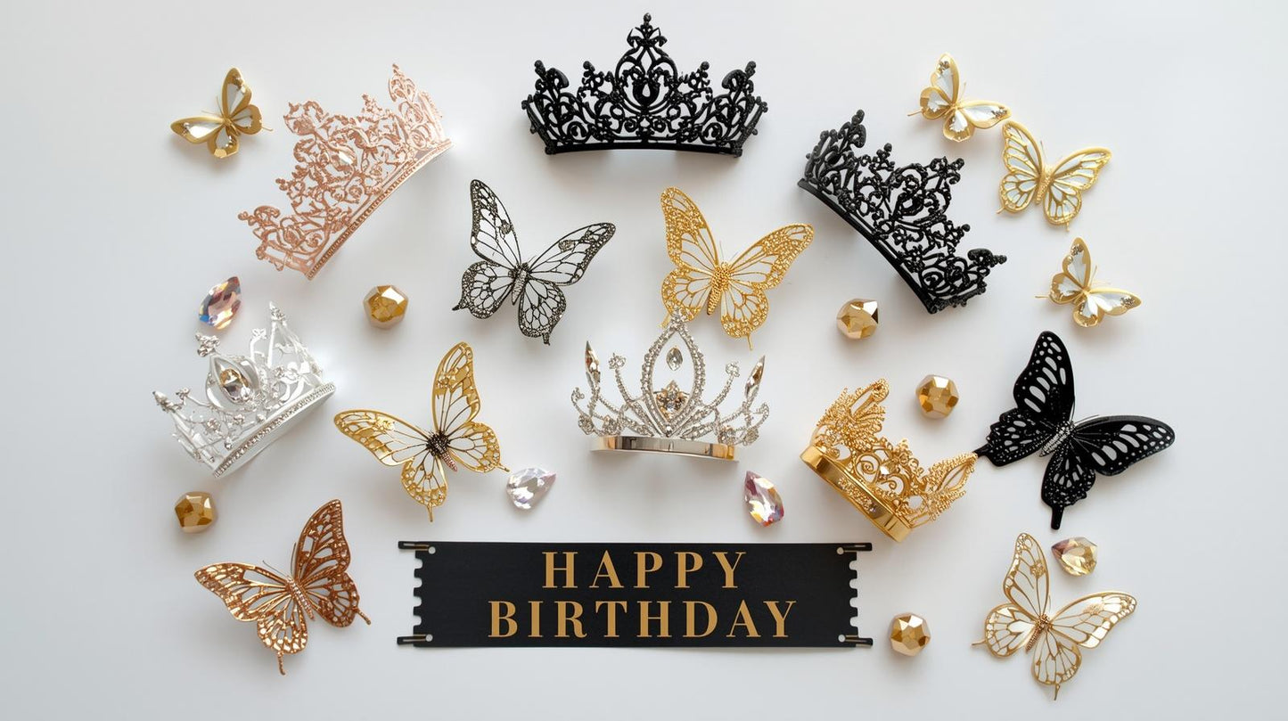Collection of decorative tiaras and butterflies and a 'Happy Birthday' banner on a light background
