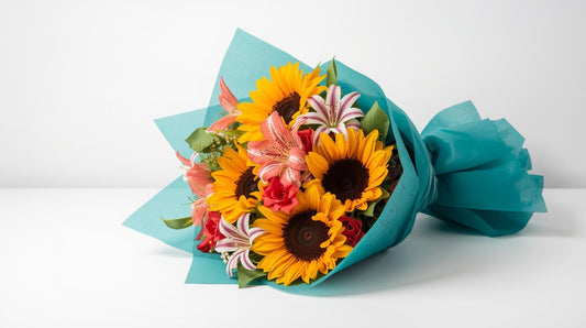 Bouquet of flowers with sunflowers and other colorful blooms wrapped in blue paper on a white background